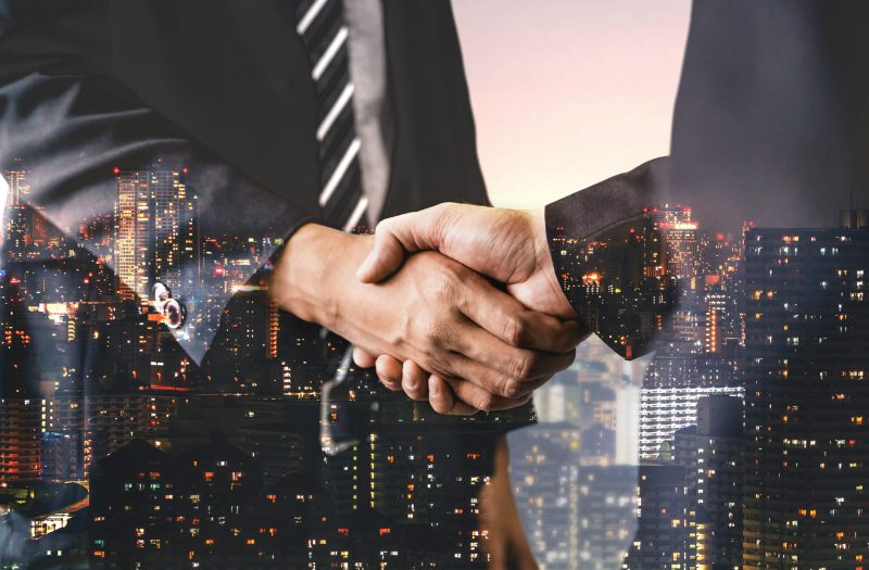 Double Exposure Image of Business and Finance Double exposure image of business people handshake on city office building in background showing partnership success of business deal. Concept of corporate teamwork, trust partner and work agreement.